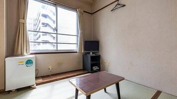 Una habitación con suelo de tatami, una mesa baja, un televisor y un calentador.