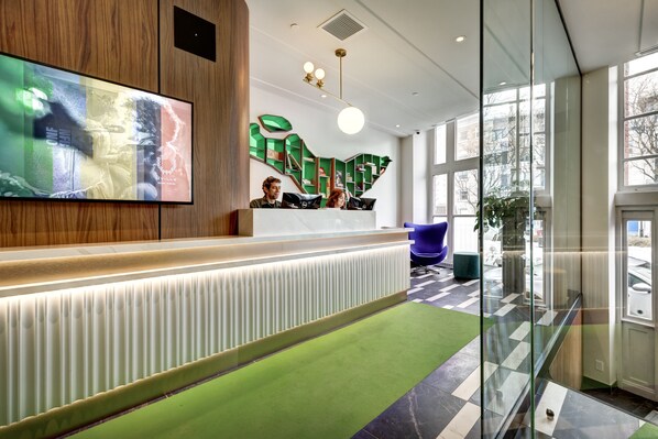 Een receptiegedeelte met een modern ontwerp, met een receptiebalie, een groot digitaal scherm en een glazen scheidingswand.