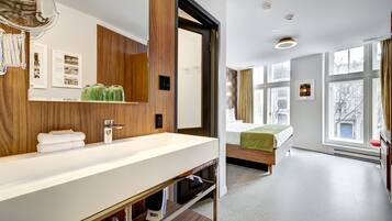 A modern bathroom with a large sink, wooden paneling, and a bed with a green towel.