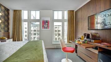 A hotel room with a bed, a desk with a computer, a chair, and a TV.