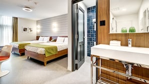 Ein Hotelzimmer mit zwei Betten, einem Badezimmer inklusive Spiegel und einem Sessel.