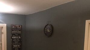 Una habitación con un sofá de cuero negro, un reloj en la pared y un cartel con una frase motivacional.