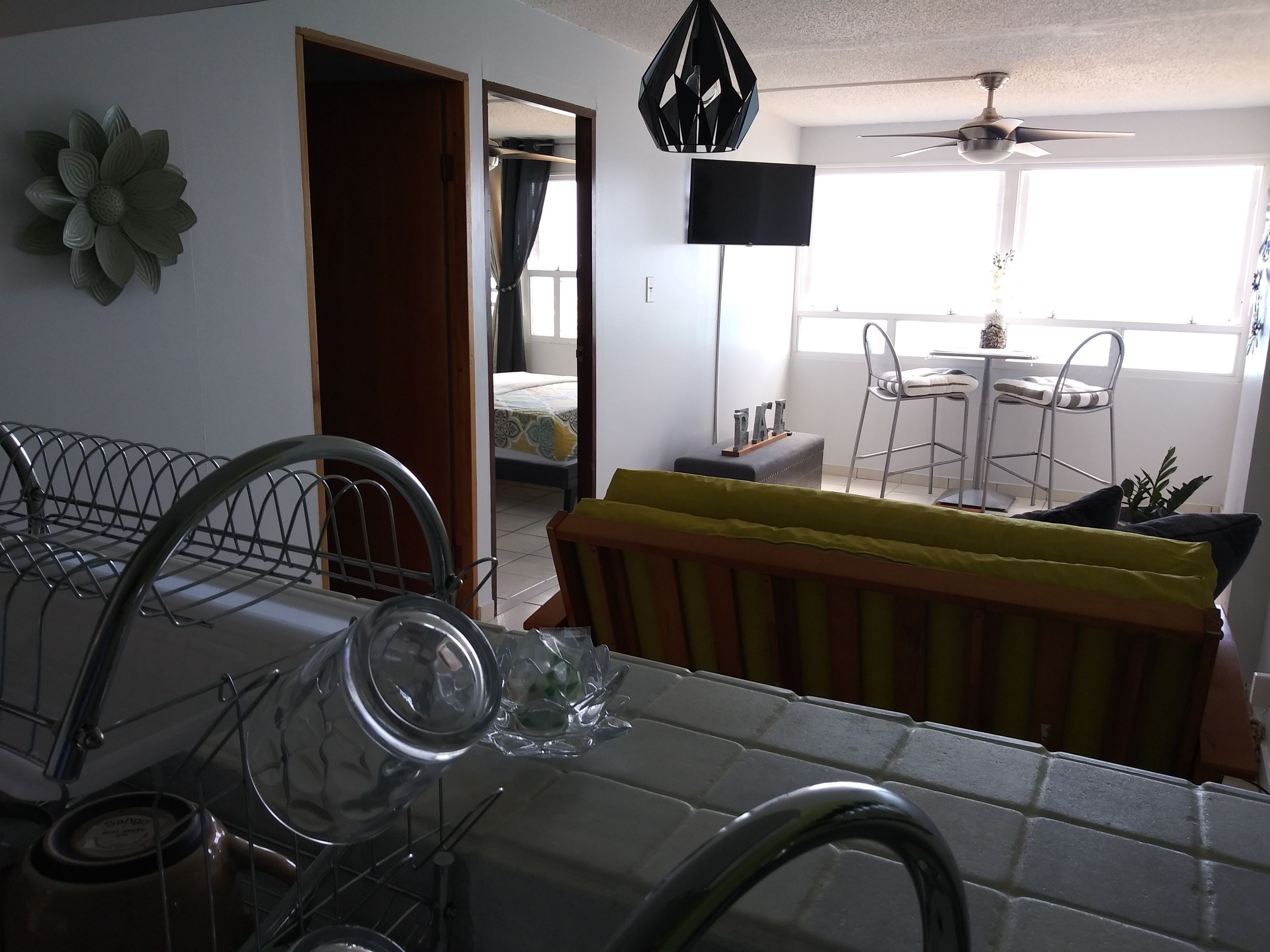 A kitchen with a sink, a dining area with chairs, a table, and a ceiling fan.