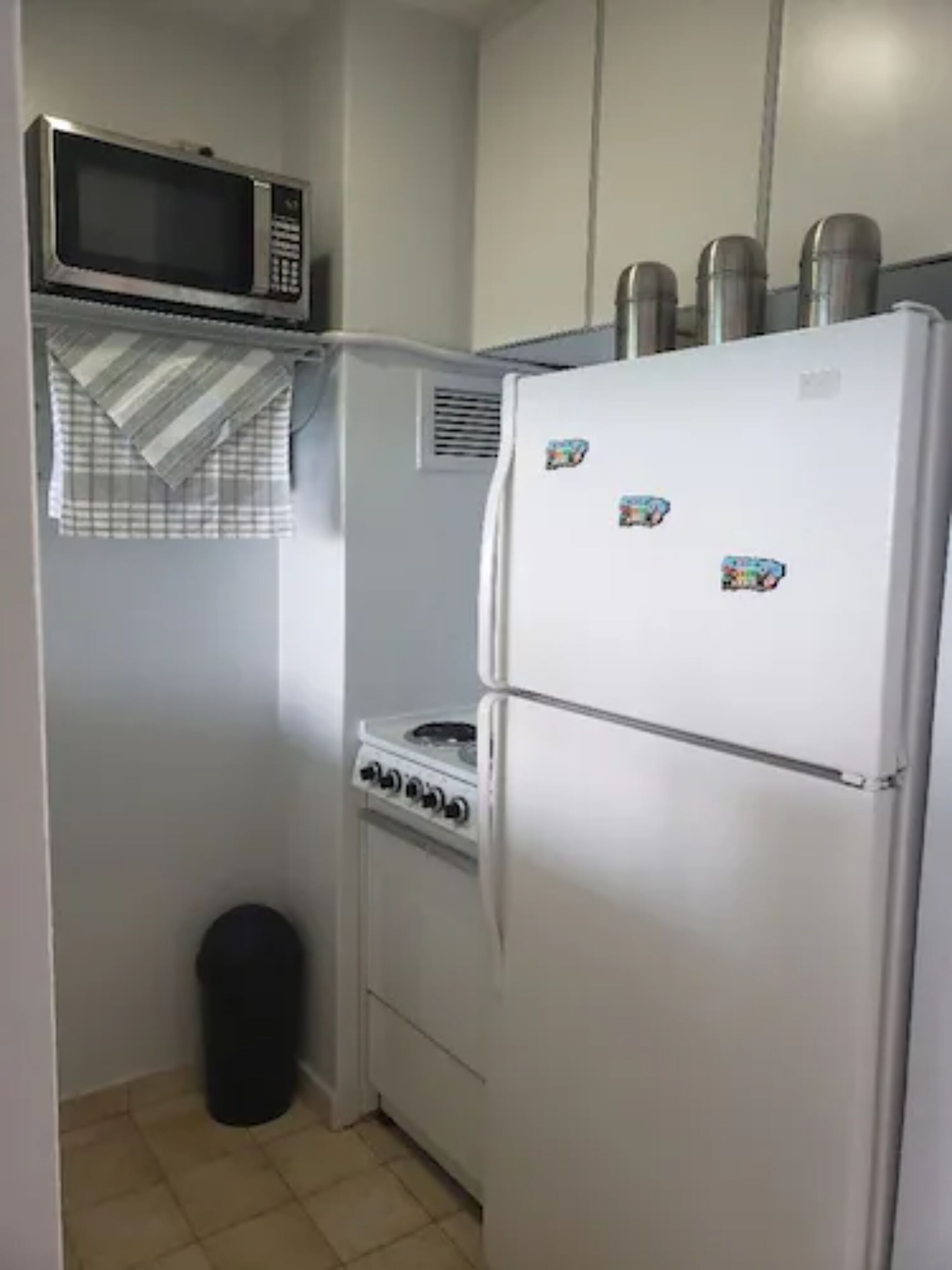 A compact kitchen with a microwave, stove, and refrigerator.