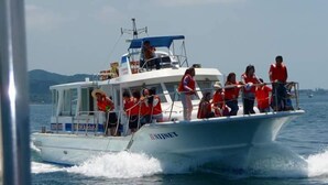 Ein Boot mit Passagieren in Rettungswesten bewegt sich auf dem Wasser.