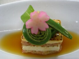 A dessert with a flower and green leaves on a white plate.