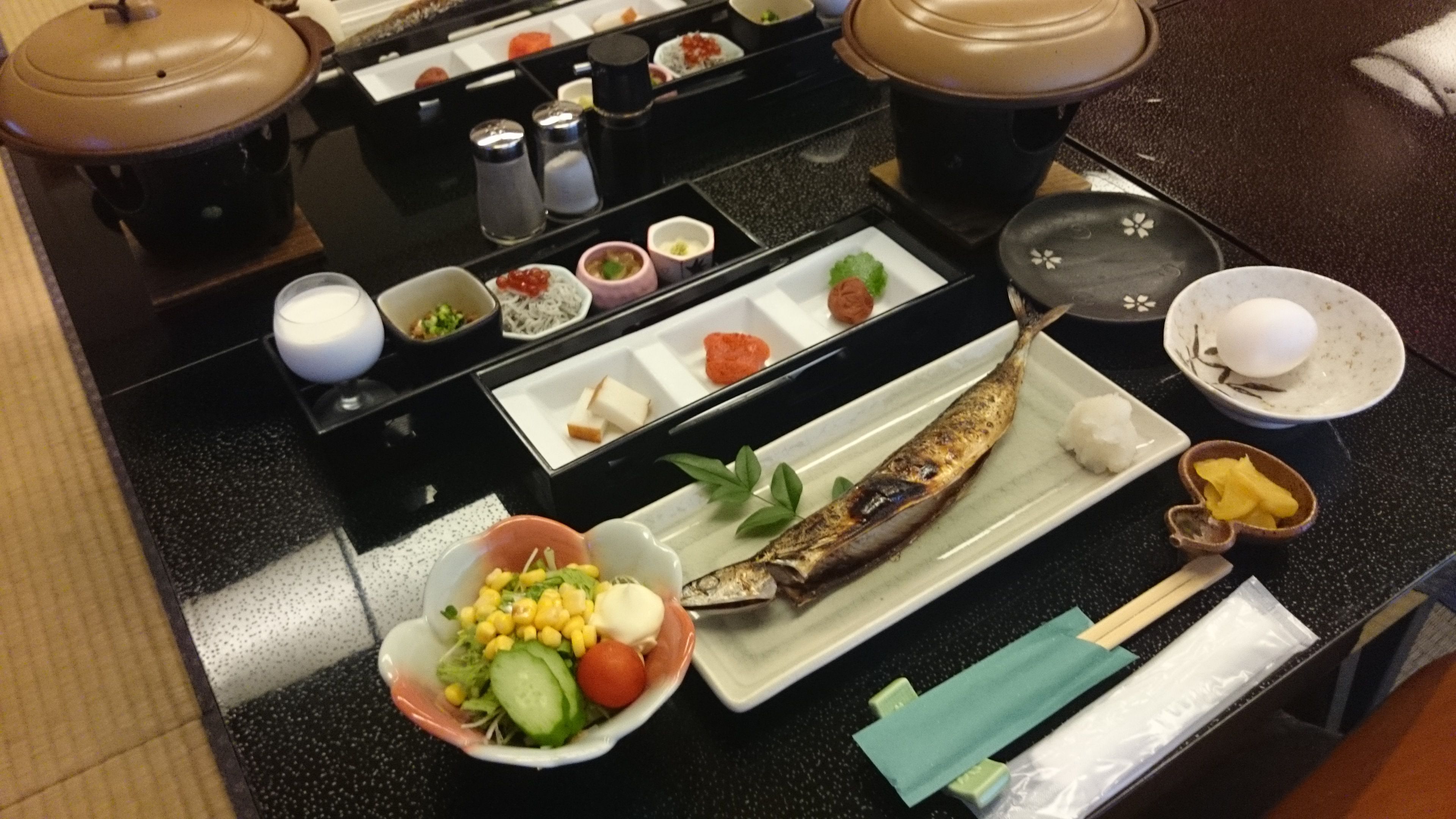A dining table with various dishes, including a whole fish, vegetables, and condiments.