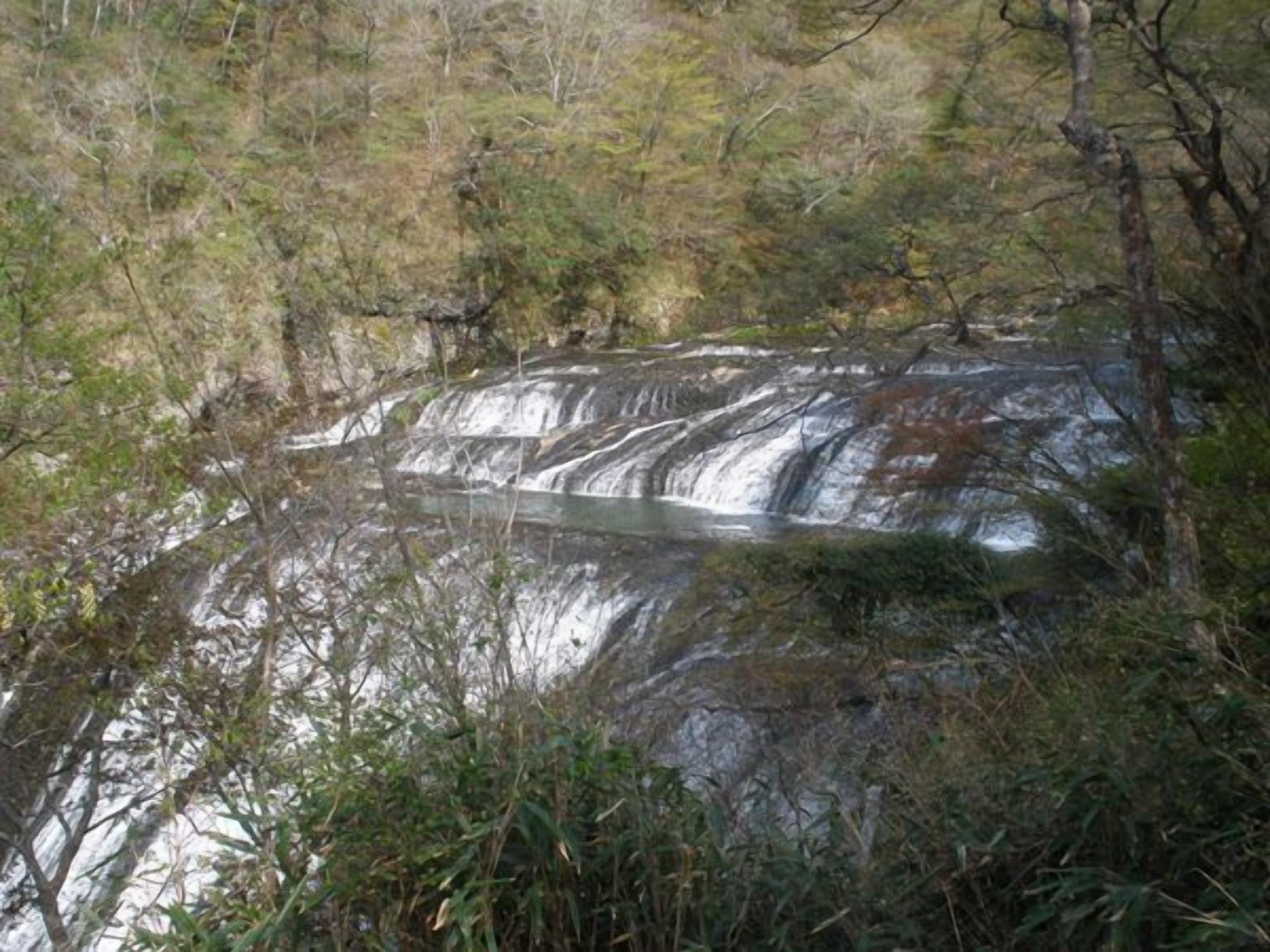 A natural landscape with a waterfall and surrounding vegetation.
