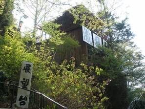 A traditional wooden building with signage, surrounded by lush greenery. - Takimikan (Daigo)