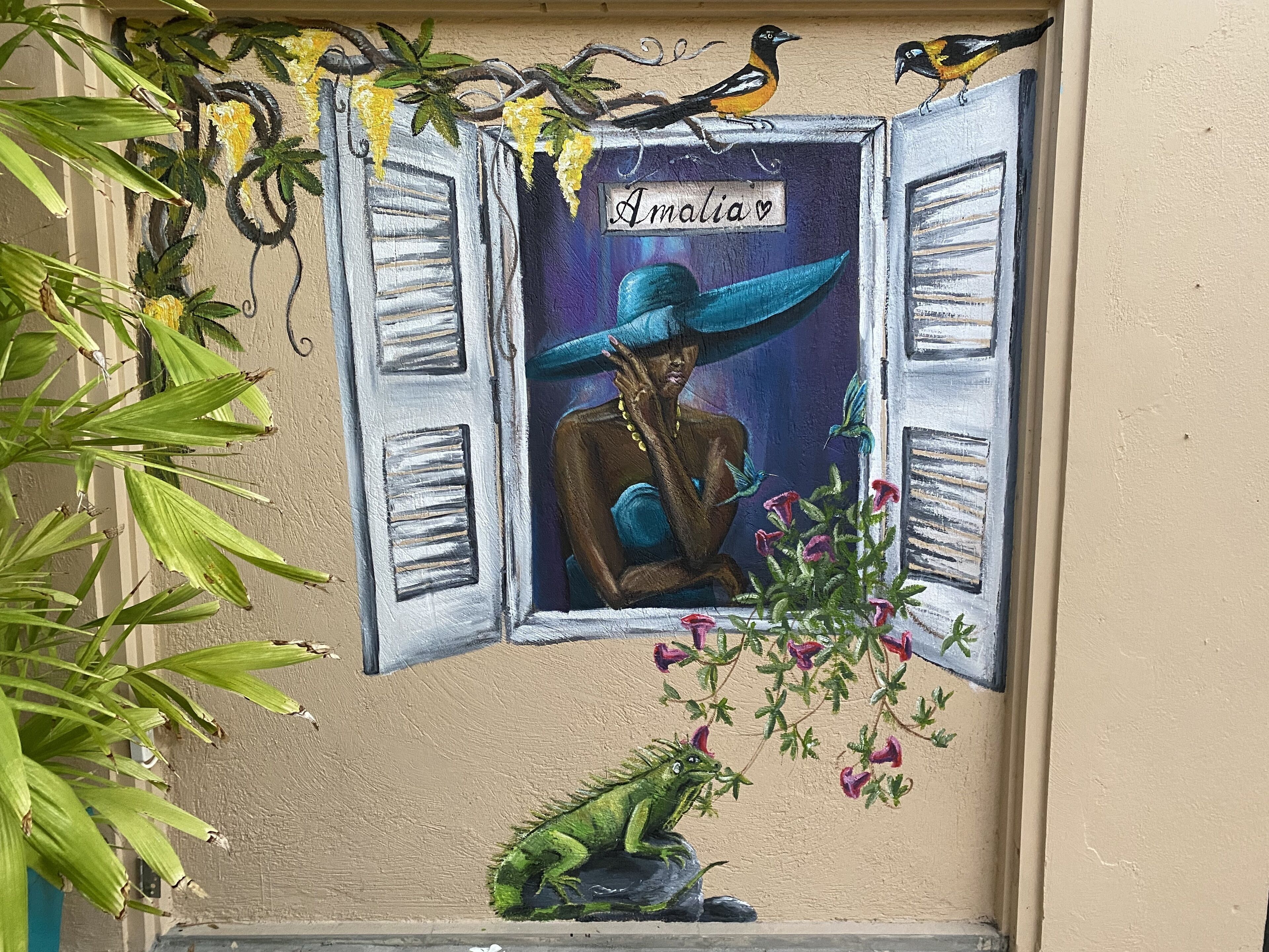 A mural with a woman wearing a hat, a bird, and a plant.