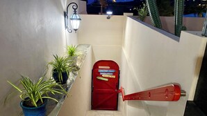 Un escalier étroit mène à une porte rouge sur laquelle est apposée une enseigne indiquant la présence d’un restaurant.