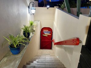 A narrow stairway leading to a red door with a sign indicating a restaurant. - Casa Amalia (Jan Thiel)