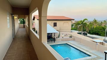 A pool area with a tiled deck, a small pool, and a seating area with a table and chairs.
