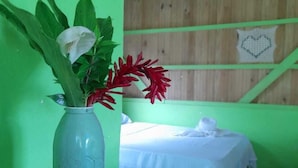 Una habitación con una cama, pared verde y techo de madera.