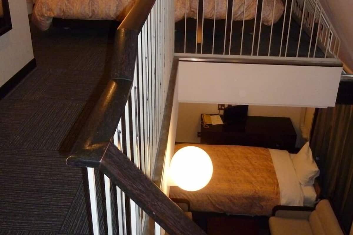A hotel room with a bunk bed, a desk with a lamp, and a framed picture on the wall.
