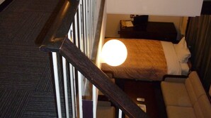 Una camera d'albergo con un letto a castello, una scrivania con una lampada e un quadro appeso al muro.