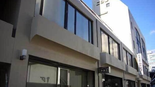 Un edificio moderno con diversi piani, ampie finestre e una segnaletica che indica un'attività commerciale.