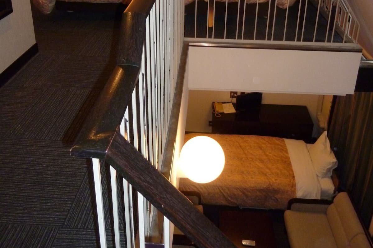 A hotel room with a bunk bed, a desk with a lamp, and a framed picture on the wall.