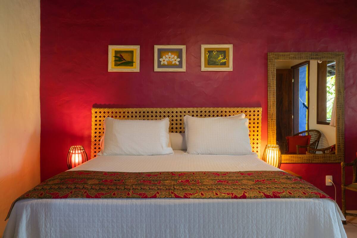 A bed with a patterned bedspread, a wooden headboard, and three framed pictures on the wall.