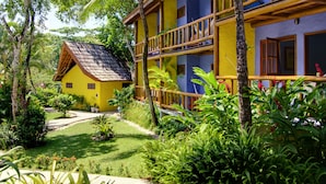 A two-story building with a balcony, surrounded by lush greenery and a well-maintained garden. - Atmosphera Pousada (Porto Seguro)