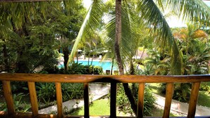 A view of a pool surrounded by lush greenery and a wooden railing. - Atmosphera Pousada (Porto Seguro)