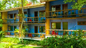 A two-story building with balconies, surrounded by lush greenery. - Atmosphera Pousada (Porto Seguro)