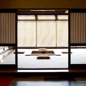 Habitació japonesa tradicional amb tatami, panells shoji i una taula baixa amb coixins.
