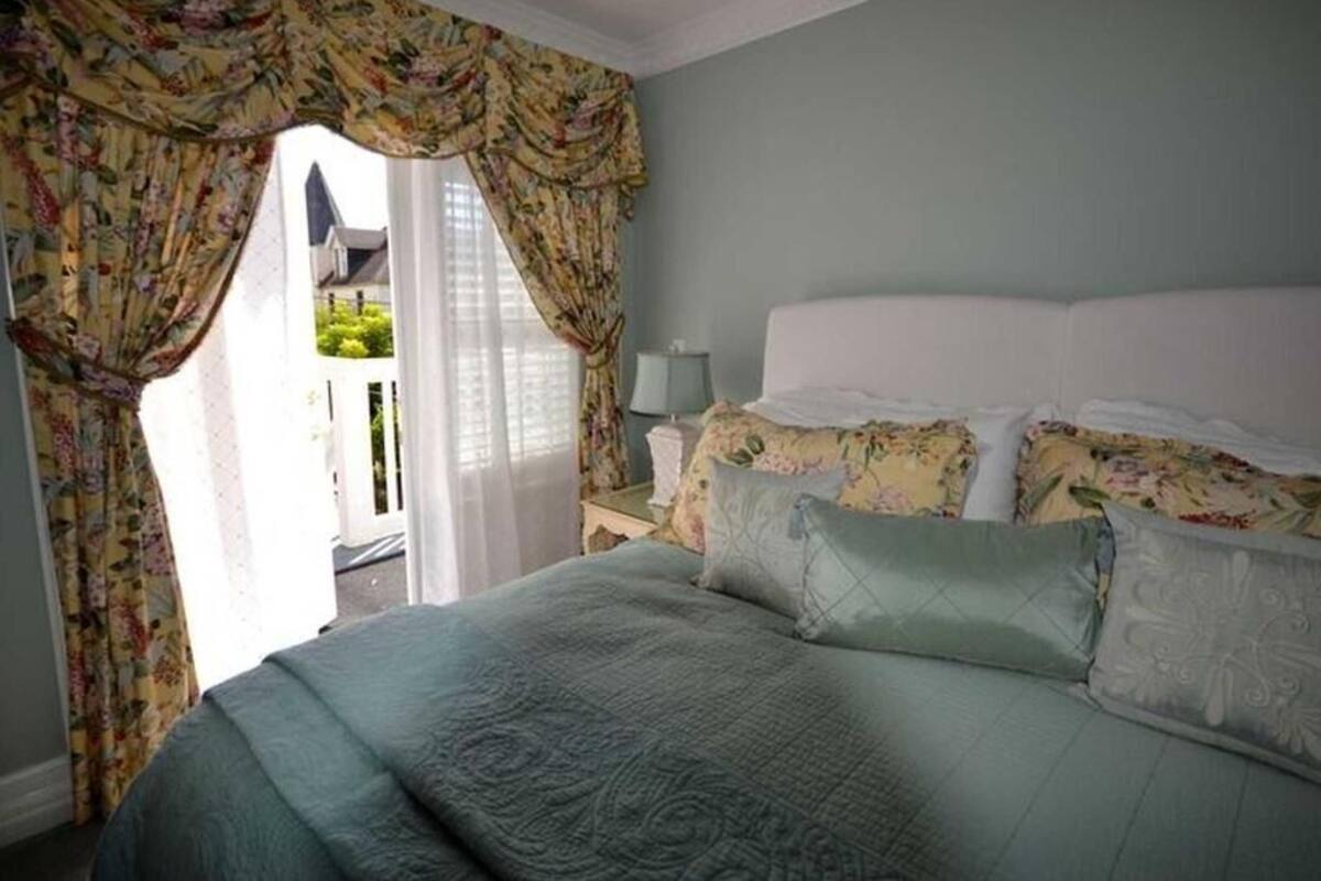 A bedroom with a bed, floral curtains, and a view of the outside.