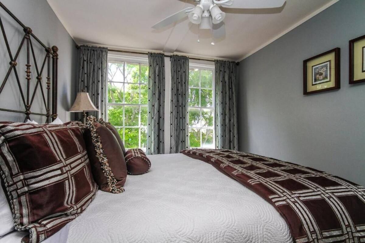 A bedroom with a large bed, a ceiling fan, and a window with curtains.