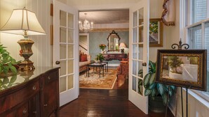 A hallway with a wooden floor, a lamp, a mirror, and a framed picture. - The Kenwood Inn (St. Augustine)