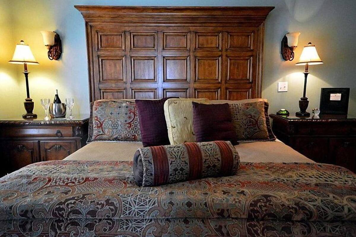 A large bed with a patterned bedspread, two nightstands with lamps, and a wooden headboard.