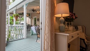 A room with a white console table, a lamp, and a vase with flowers. - The Kenwood Inn (St. Augustine)