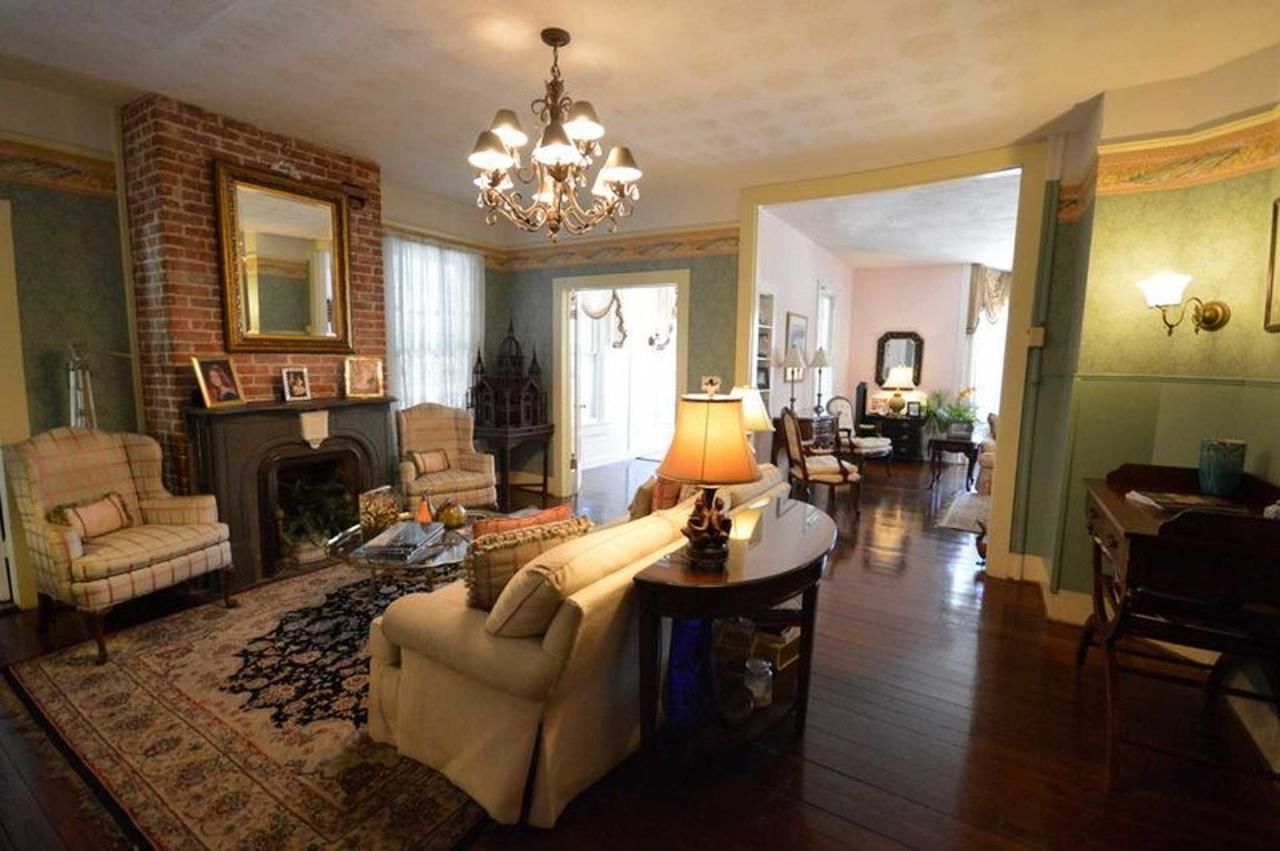 A spacious living room with a fireplace, a chandelier, and a cozy seating area.