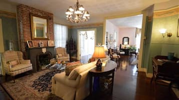 A spacious living room with a fireplace, a chandelier, and a cozy seating area.
