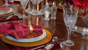 A dining table set with red candles, crystal glassware, and a floral centerpiece. - The Kenwood Inn (St. Augustine)