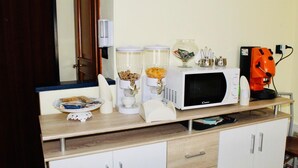 A kitchenette with a microwave, coffee maker, and a small oven. There is a plate with food and a glass jar on the counter. - Beauty house (Reggio Calabria)