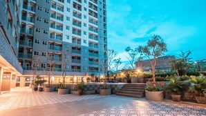 A modern hotel courtyard with a patterned floor, potted plants, and a staircase leading to an upper level. - OYO Flagship 728 Baileys Apartment (South Tangerang)