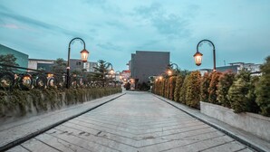 A paved pathway with street lamps and hedges on both sides, leading towards a large building. - OYO Flagship 728 Baileys Apartment (South Tangerang)