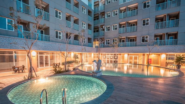 A courtyard with two swimming pools, a lounge area, and a building with balconies. - OYO Flagship 728 Baileys Apartment (South Tangerang)