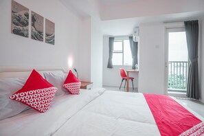 A hotel room with a bed, a desk, and a balcony.