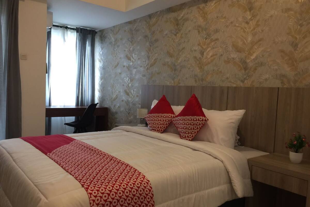 Una habitación de hotel con una cama grande, un escritorio y una ventana con cortinas.
