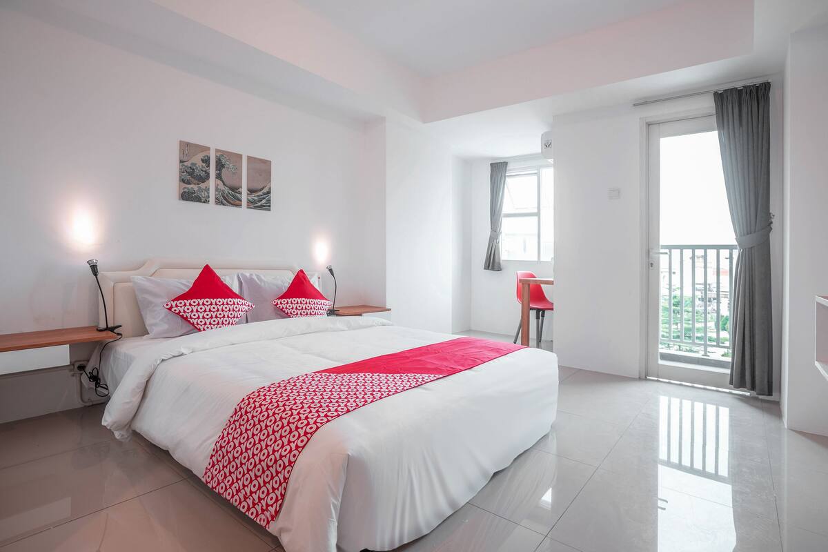 Un dormitorio amplio con una cama grande, una mesita de noche, una silla y un balcón con vistas.