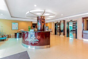 A hotel reception area with a curved counter, a sign for 'Collection Signature Stays by OVO', and a framed map on the wall. - Collection O 7 Hotel Melawai (Jakarta)