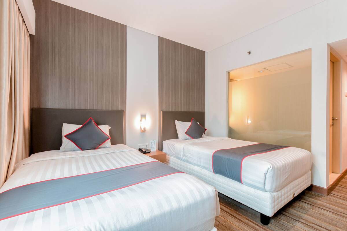 A hotel room with two beds, a nightstand, and a large mirror.