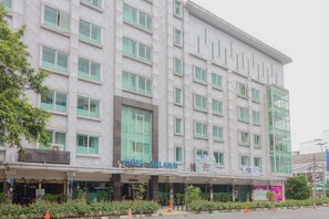 A multi-story hotel with a modern facade, large windows, and a sign reading "HOTEL MELAWAI".