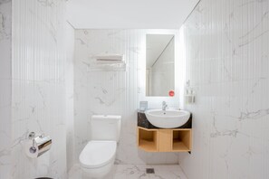 A bathroom with a white toilet, a sink, and a mirror. - Collection O 7 Hotel Melawai (Jakarta)