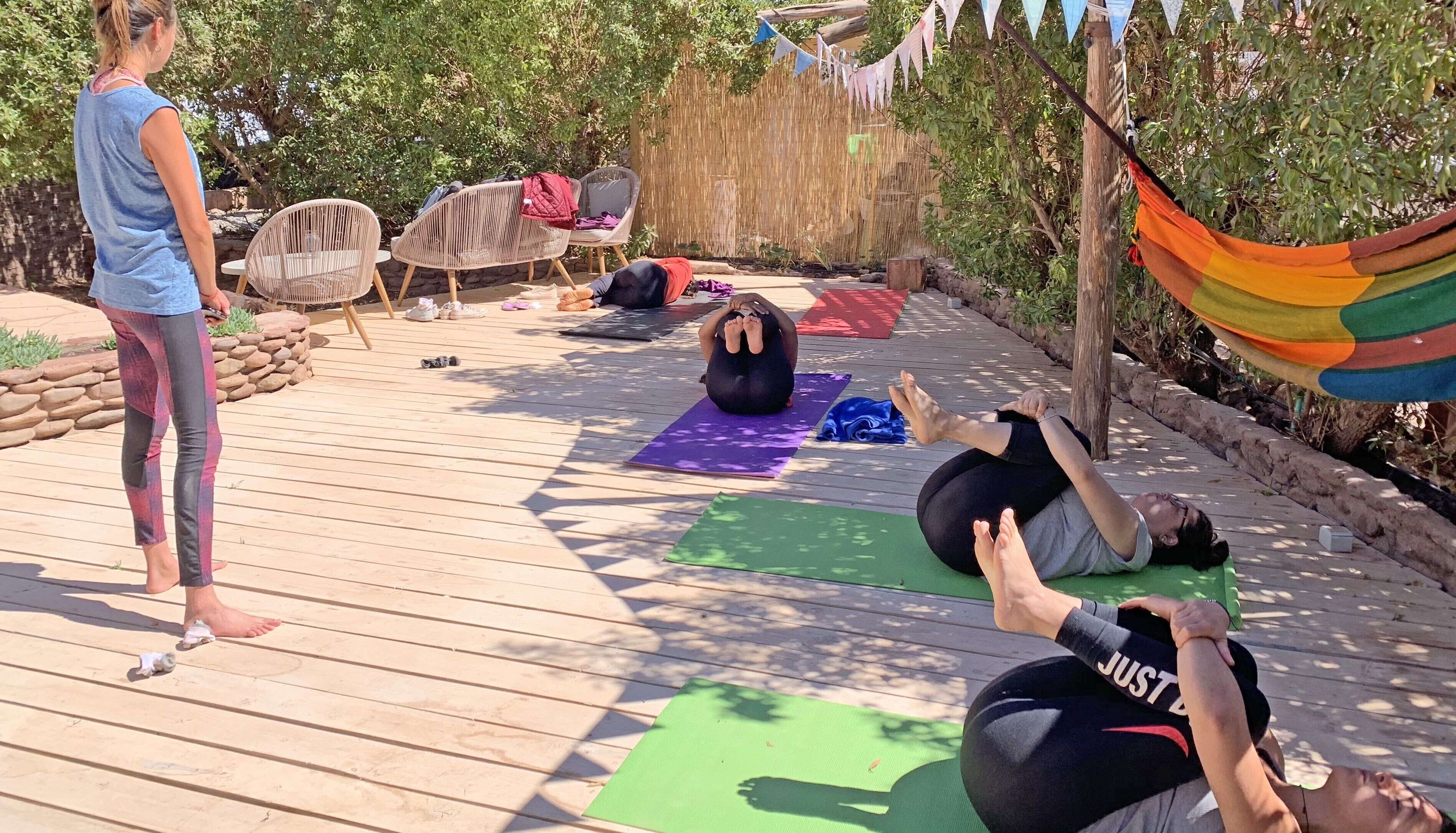 A wooden deck with yoga mats and people practicing yoga.