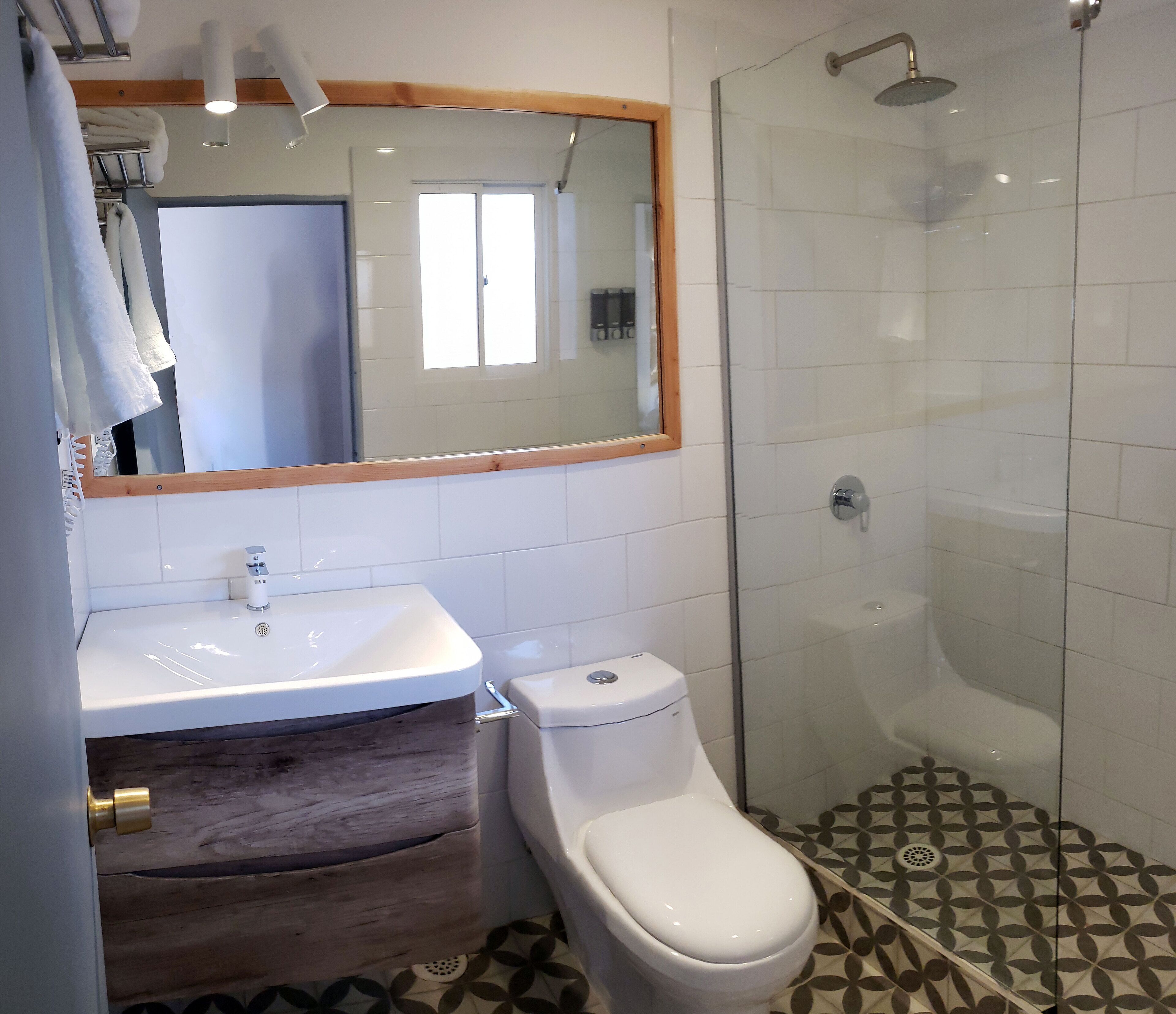 Un baño con lavamanos blanco, inodoro y ducha con mampara de vidrio.