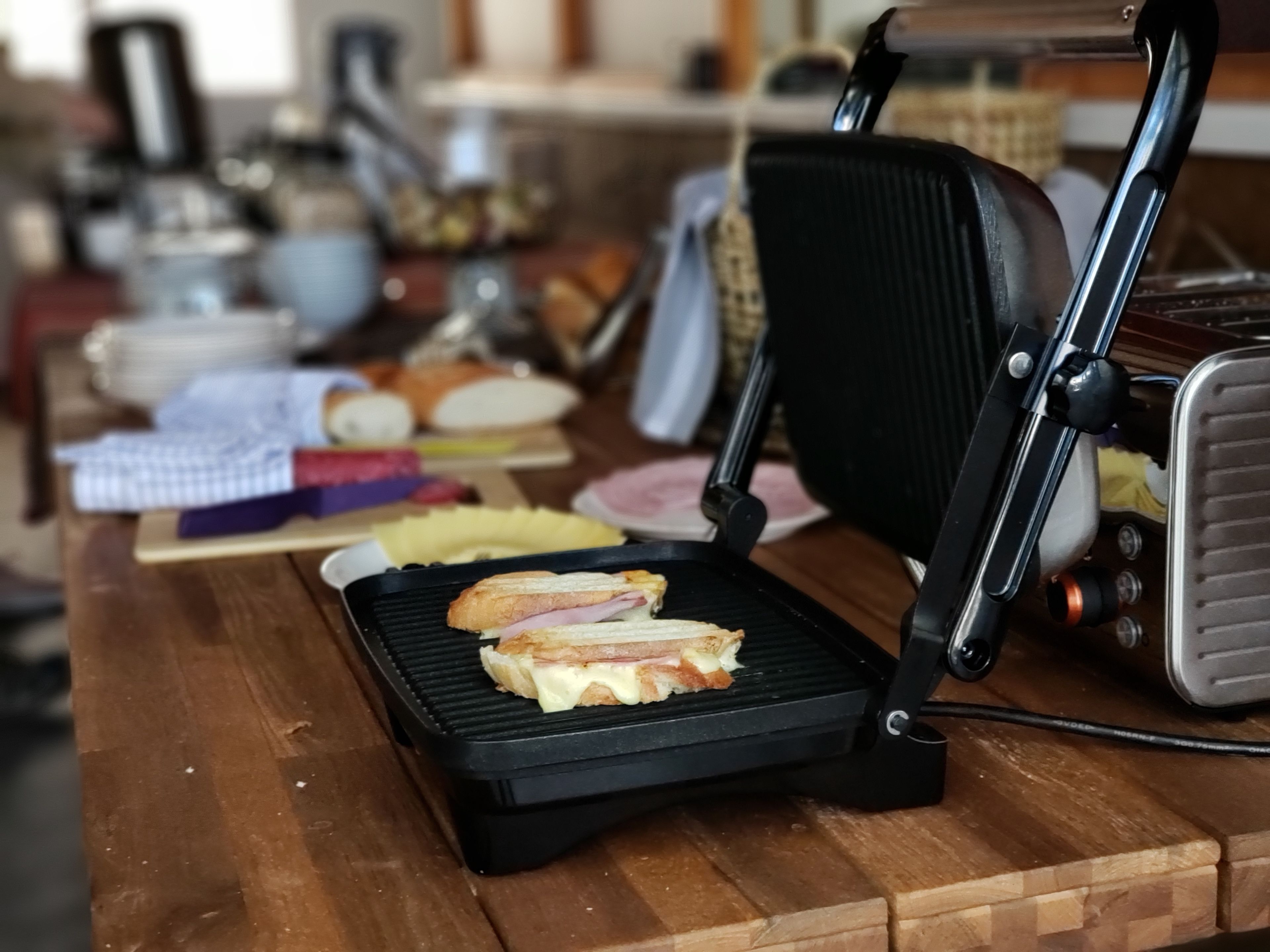 Ein Sandwich auf einem Grill, ein Holztisch und ein Stuhl.