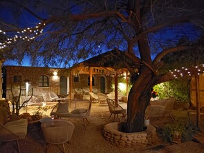 An outdoor patio area with stone walls, wicker furniture, and string lights. - Jardin Atacama (San Pedro de Atacama)